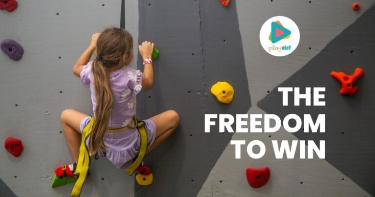 A child climbing a rock wall at Playalot® Durbanville, with the text "THE FREEDOM TO WIN" overlaid.