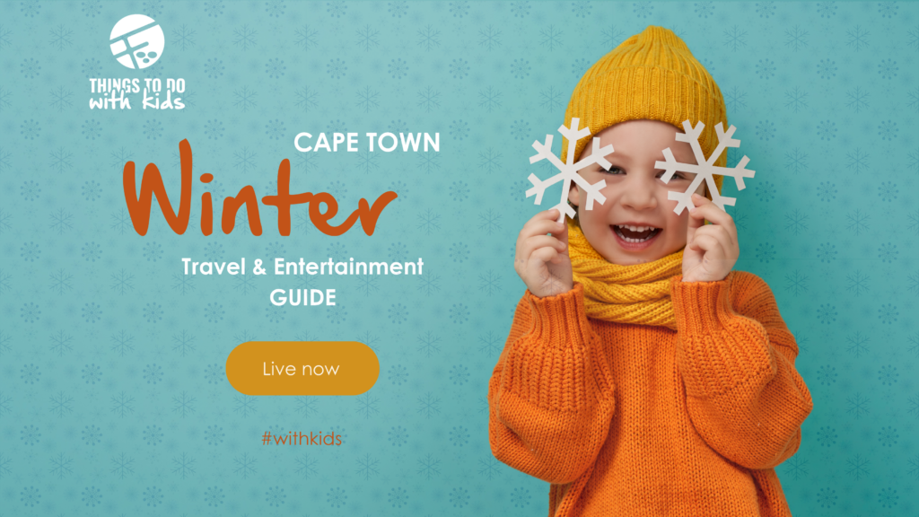 Smiling child in orange winter clothing holding paper snowflakes for the Cape Town Winter Travel and Entertainment Guide by Things to Do With Kids.
