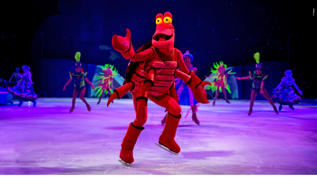 Little Mermaid's Sebastion from Disney On Ice performing on ice during Mickey’s Search Party show, skating on a brightly lit rink in a live theatrical Disney ice performance.