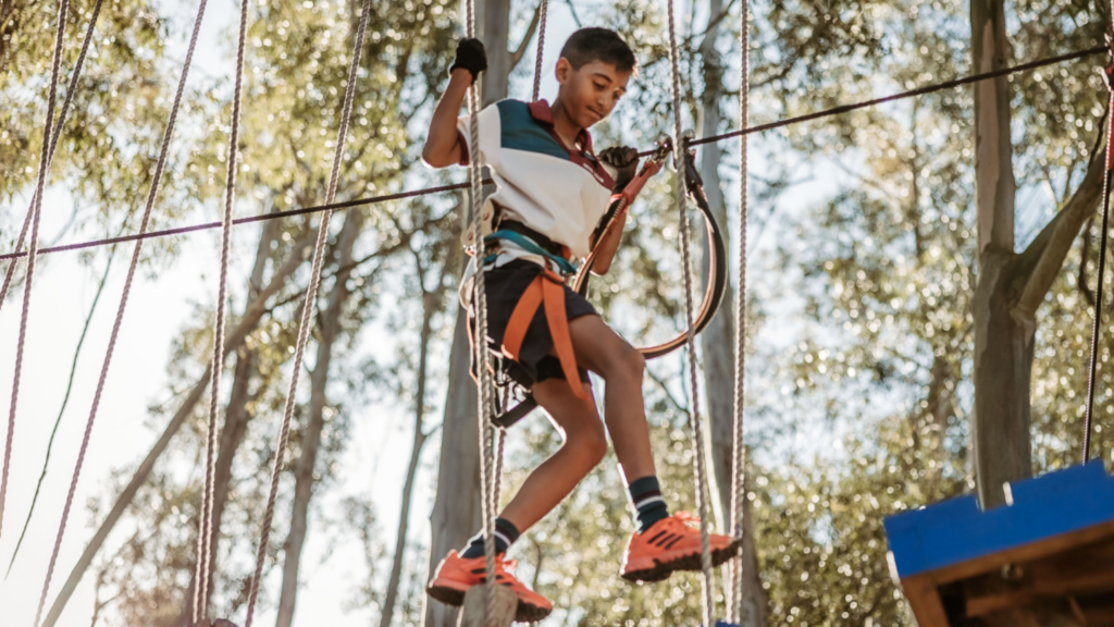 Child climbing a treetop obstacle course at Acrobranch, a fun outdoor winter adventure for families in Cape Town.