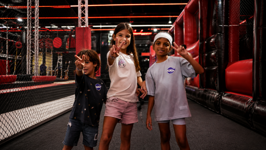 Three children smiling at Total Ninja indoor obstacle park, a winter holiday club activity for active kids in Gauteng.