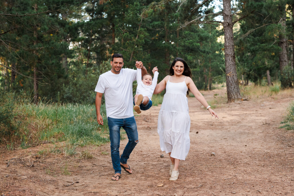 Happy family walking through a forest with their child during a relaxed family photo session by Chasing Light Photography.